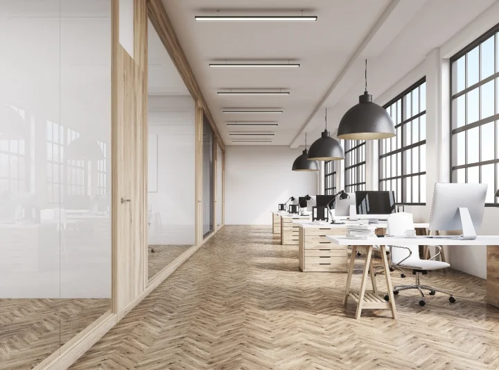 En modern kontorsmiljö med en minimalistisk design, full av eleganta skrivbord, bekväma stolar, stora fönster och ljus belysning. Kontorsinredning Göteborg.