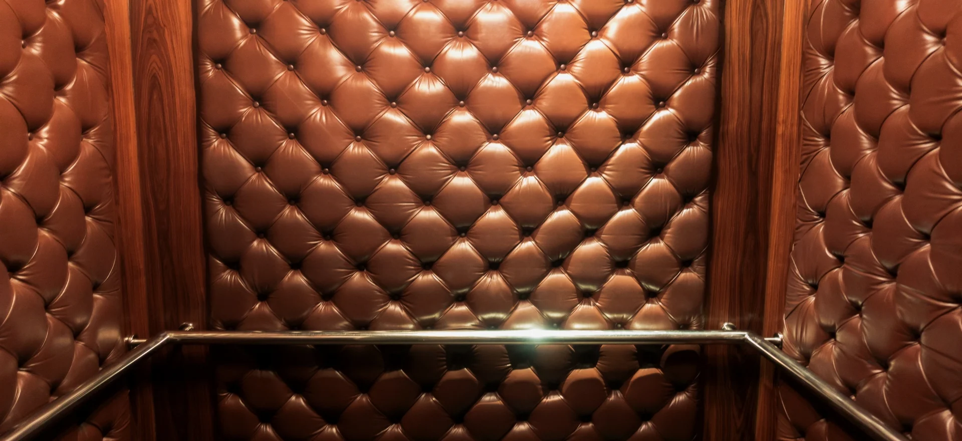 En hisskorg med smidiga väggar klädda i mjukt brun läder. En elegant interiör som ger en lyxig och bekväm hissupplevelse.